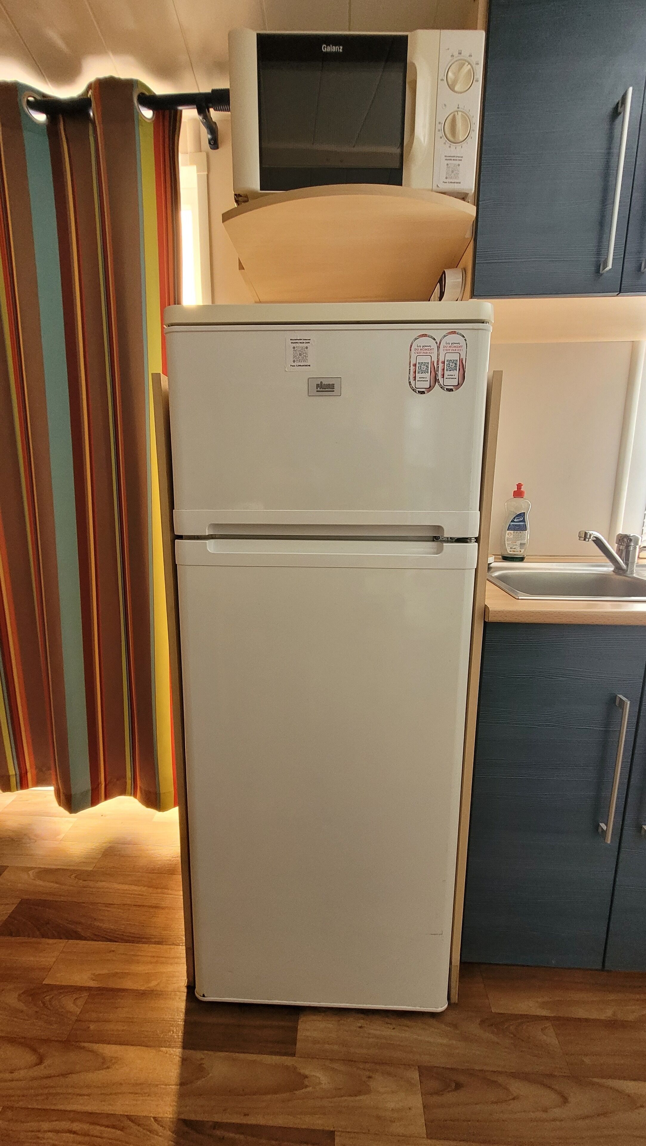 A compact kitchen with a white refrigerator, a microwave, and a sink.