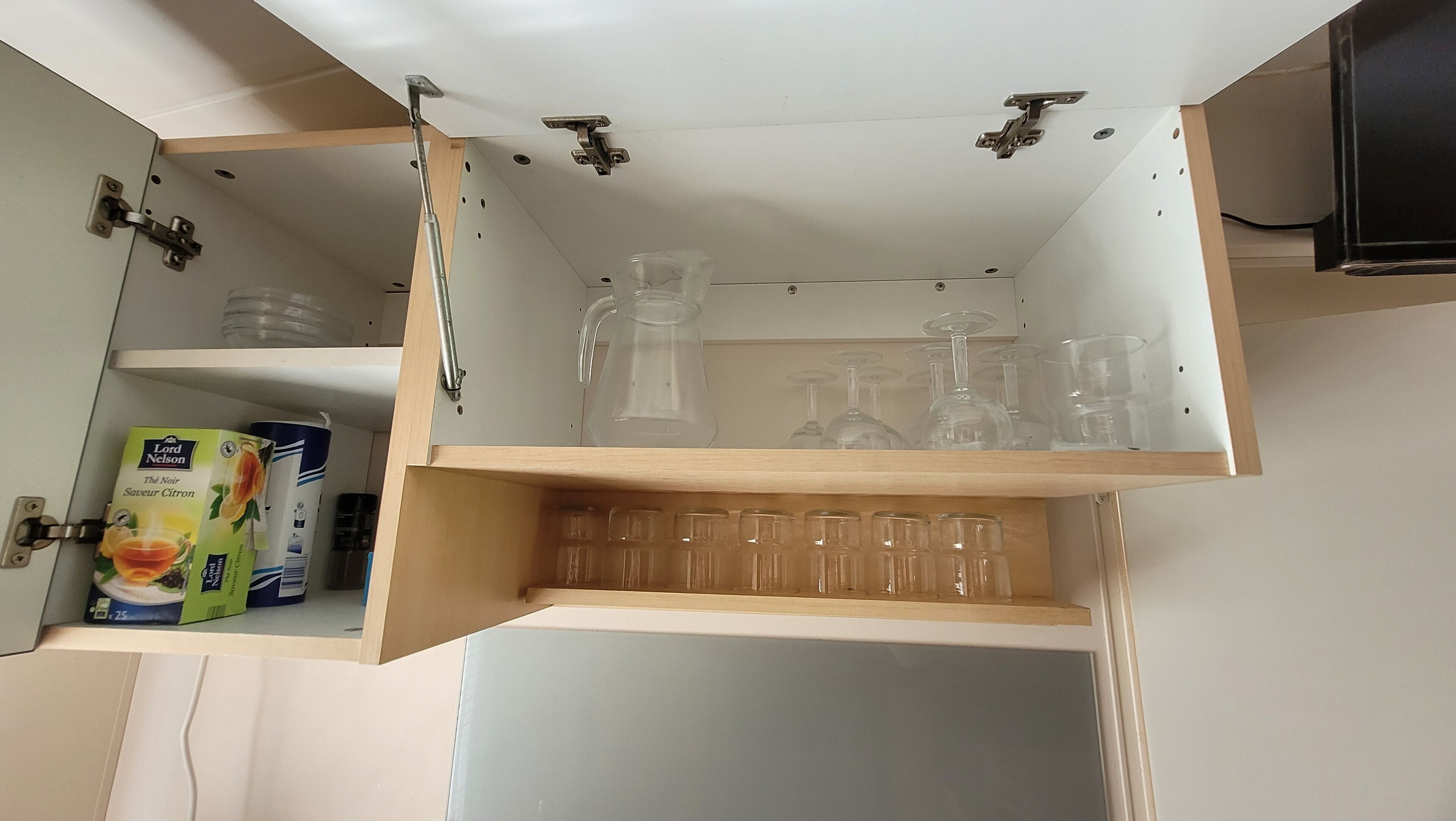 Un meuble de cuisine comprenant un porte-bouteilles, une carafe en verre et une boîte de thé.