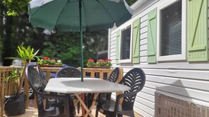 An outdoor patio with a table and chairs, a green umbrella, and potted plants. - Mobilhome Nicolette, 15 Minutes de Europa-park! (Boofzheim)