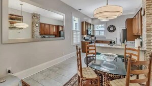 A modern kitchen with wooden cabinets, a large island, and a dining area with a glass table and chairs.