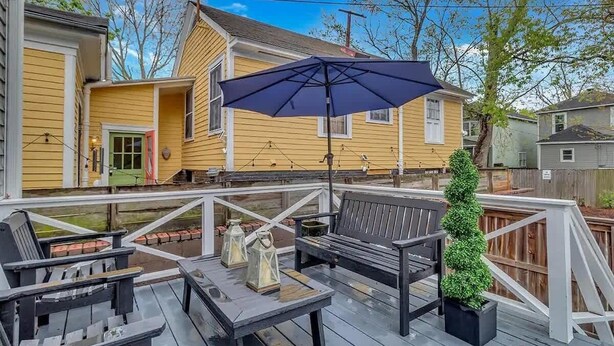 A wooden deck with outdoor furniture, including a bench and chairs, and a table with lanterns.