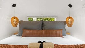 Een slaapkamer met een bed, twee bedlampen en uitzicht op groen buiten.