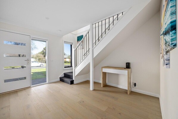 A modern interior with a staircase, a door with glass panels, and a view of the outdoors.