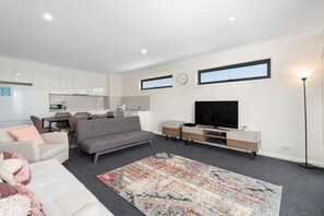 A modern living room with a sofa, television, and a rug.