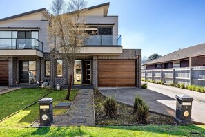 A modern two-story house with a garage, a balcony, and a well-maintained lawn.