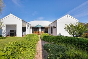 Una casa de dos pisos con un patio techado y un sendero de ladrillo que conduce a la entrada.
