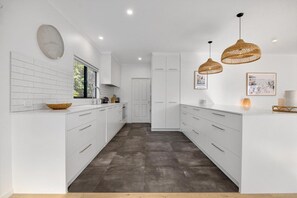 Una cocina moderna con armarios blancos, piso oscuro e iluminación colgante.