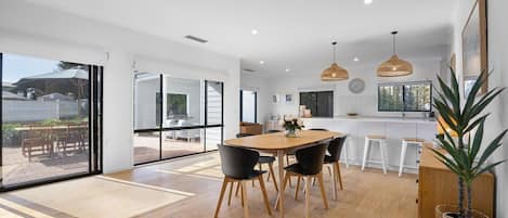 Una cucina moderna con zona pranzo, ampie finestre e vista sull'esterno.