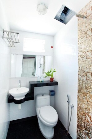 Een kleine badkamer met een witte wastafel, toilet en douche.