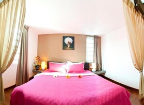 Een hotelkamer met een groot bed, een schilderij aan de muur en gordijnen voor de ramen.