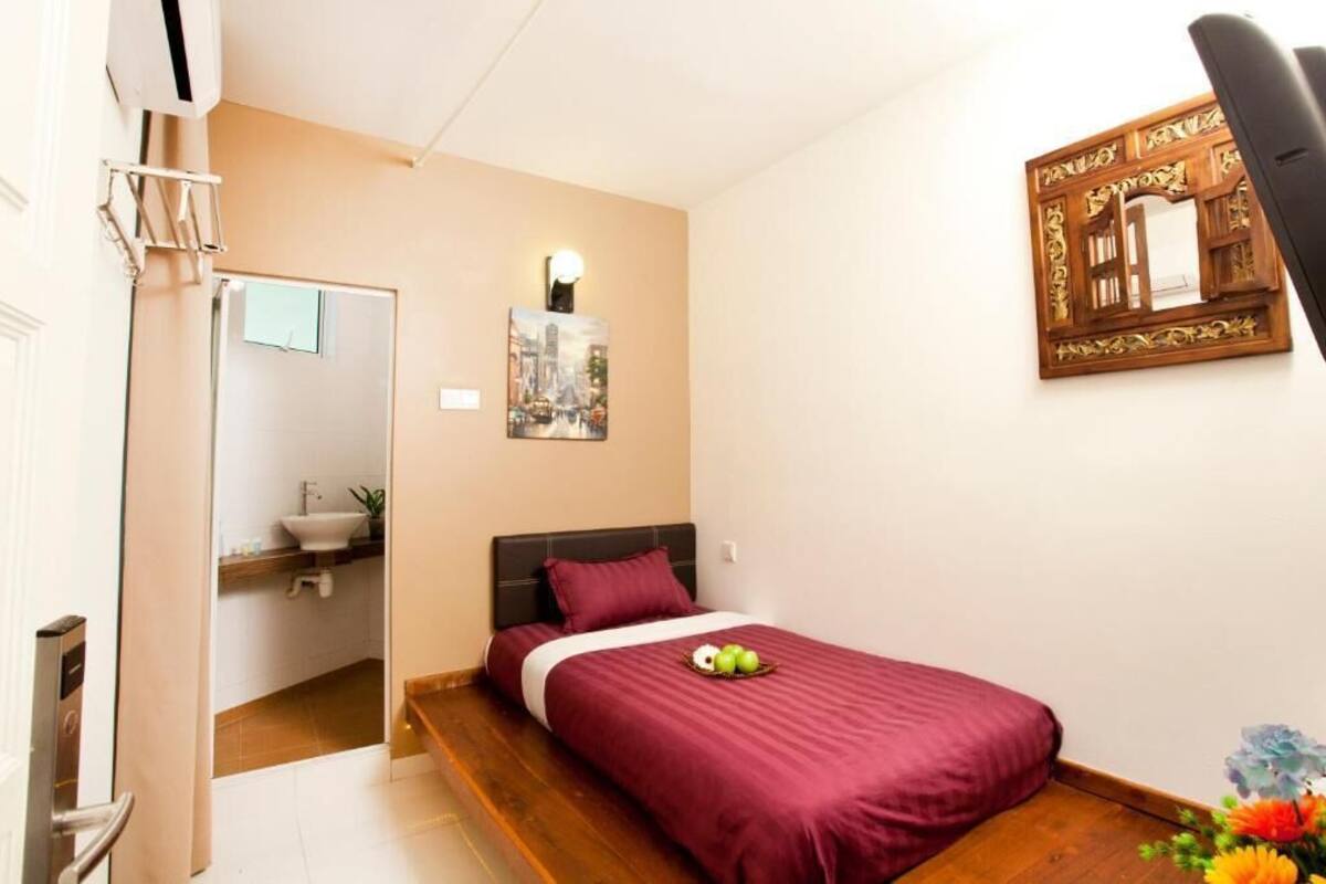 A bedroom with a bed, a nightstand, a mirror, and a wall-mounted light fixture.
