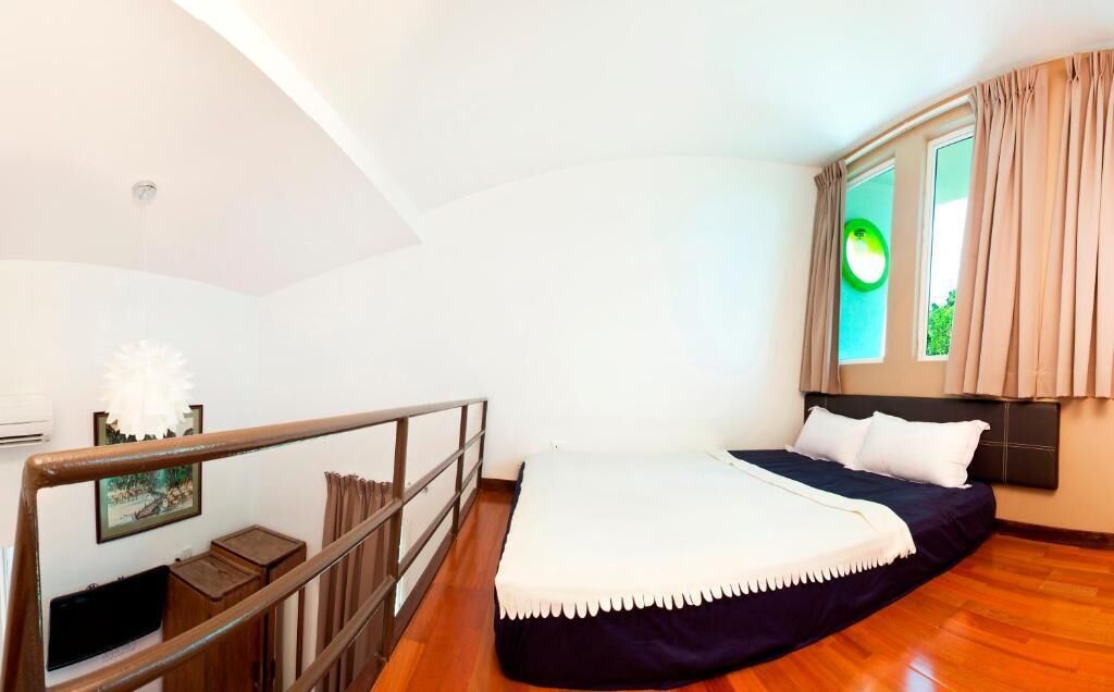 A bedroom with a bed, a window with curtains, a wooden floor, and a white ceiling.