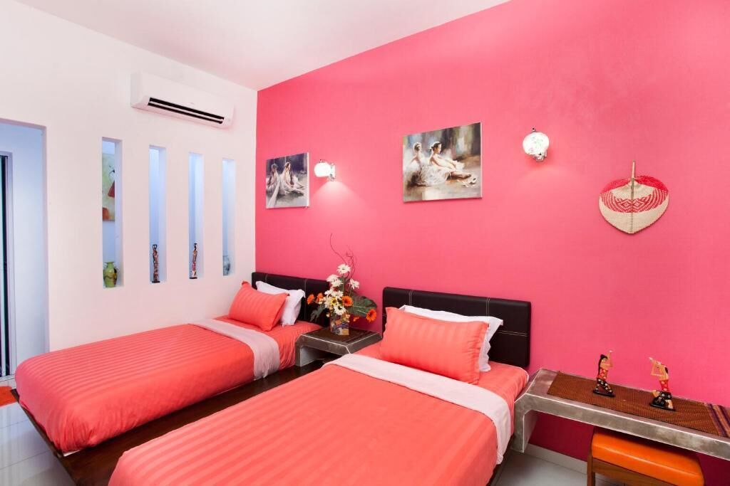 A hotel room with two beds, a pink wall, and artwork.