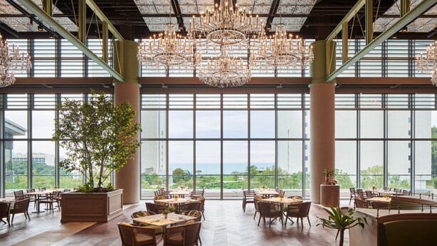A spacious dining area with multiple tables and chairs, large windows offering a view of the city, and a large chandelier hanging from the ceiling. - Ananti At Busan Village (Busan)