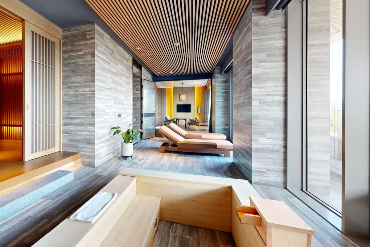 A modern interior with a wooden ceiling, a seating area with cushions, and a large window.