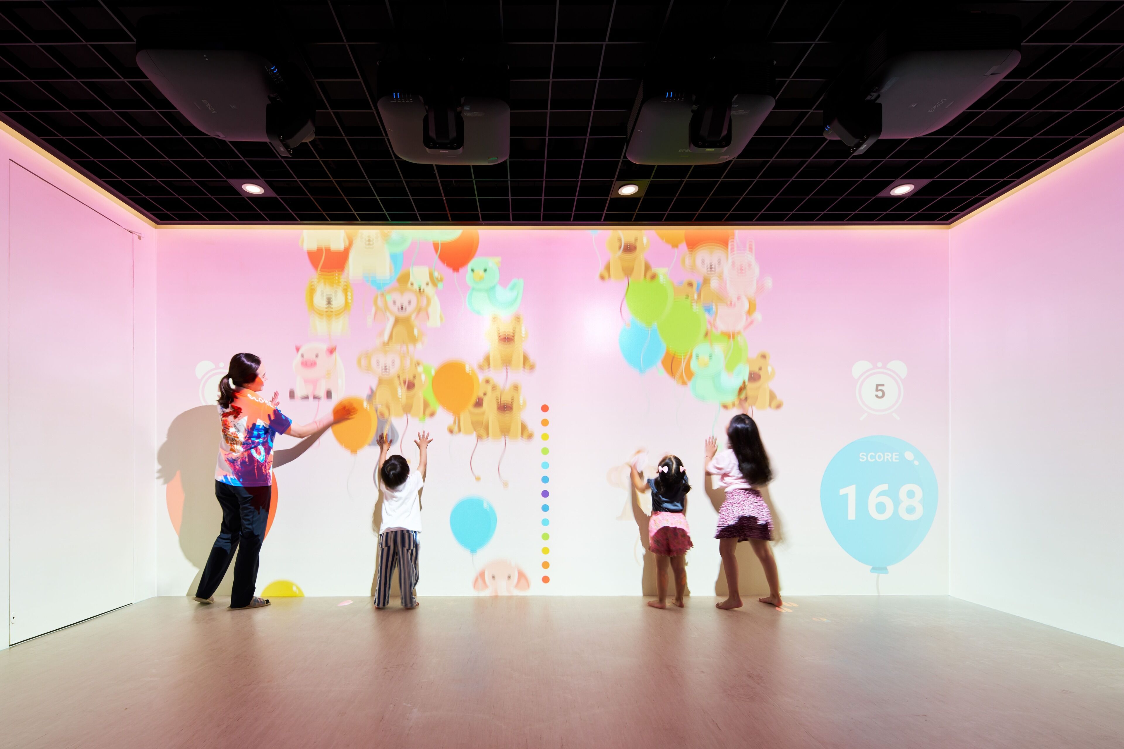 A room with a pink wall and a projection of cartoon characters and balloons.