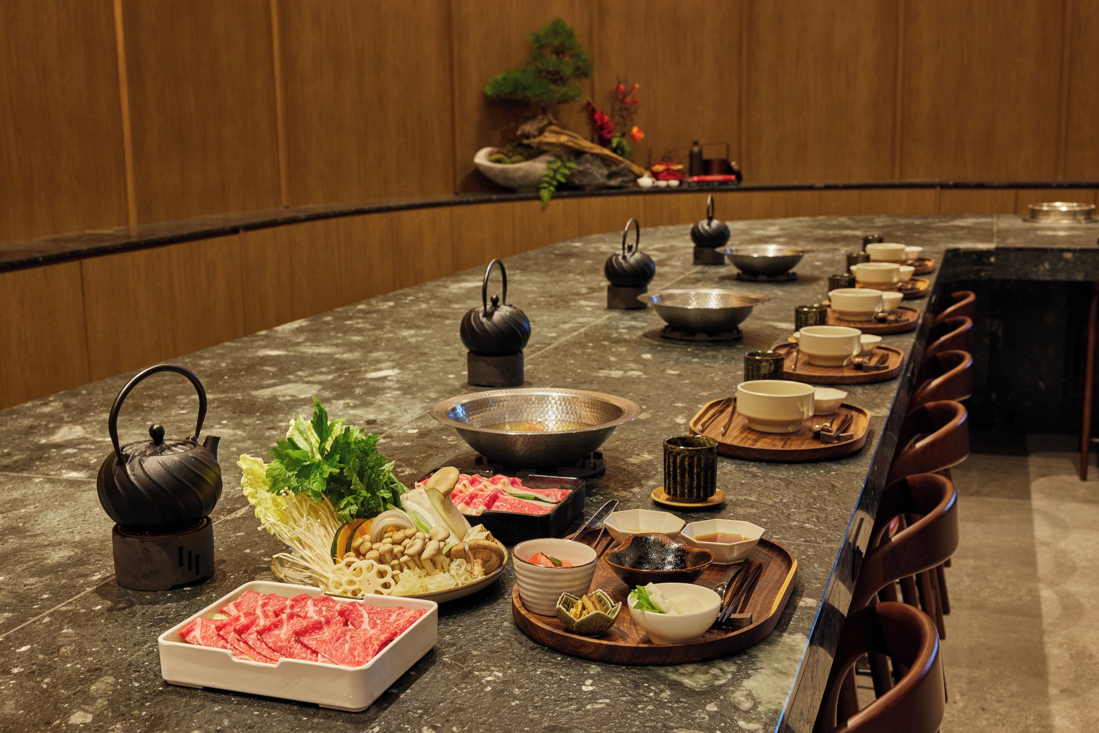 A restaurant setting with a long counter, various dishes, and teapots.