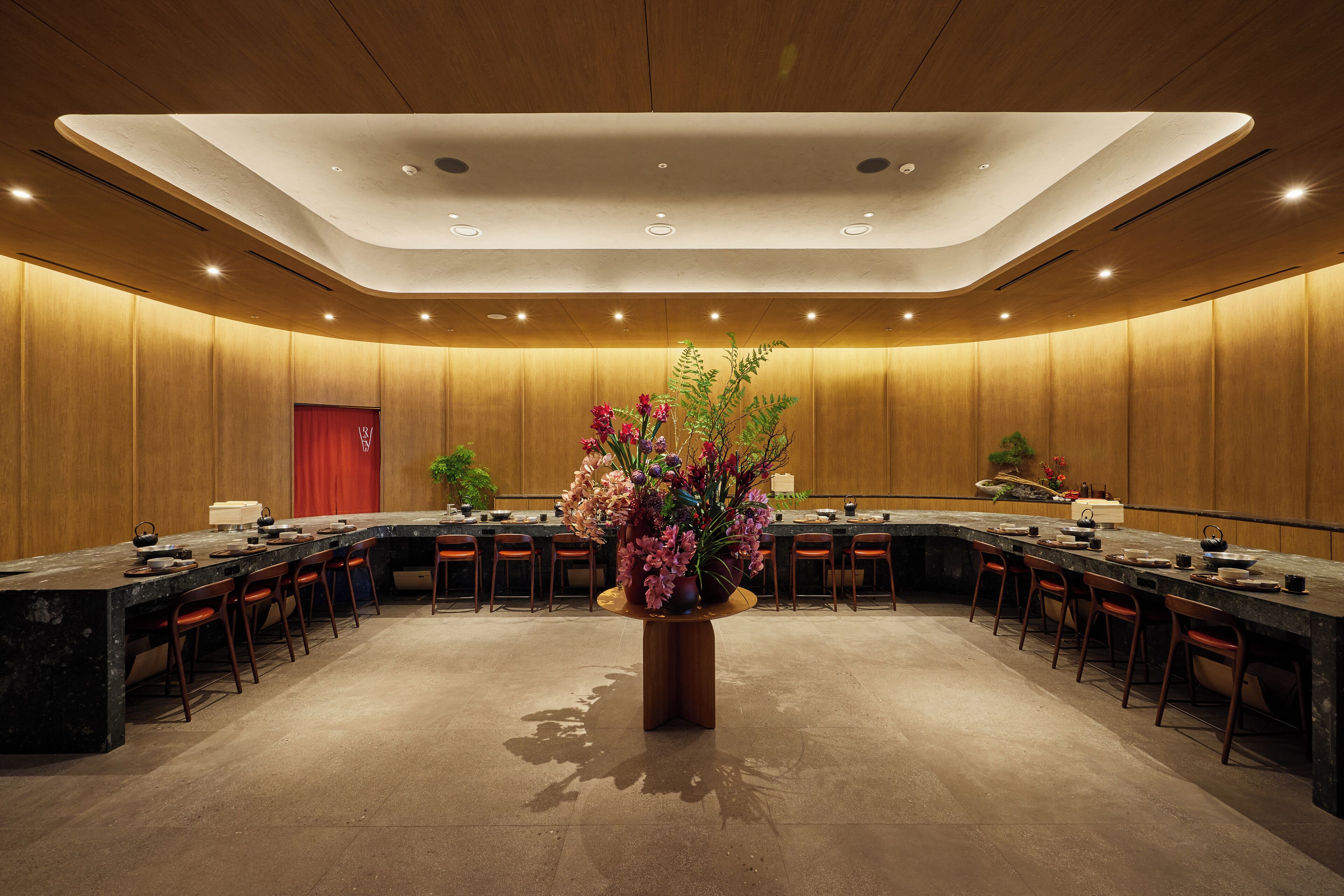 A conference room with a long table, multiple chairs, and a central floral arrangement.