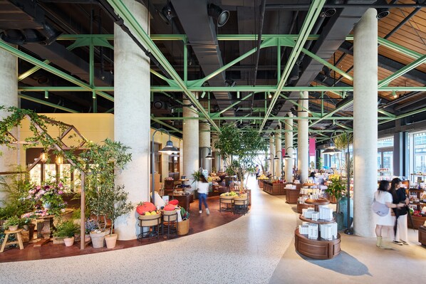 Un mercado interior espacioso con varios puestos, plantas en macetas y un pasillo central.