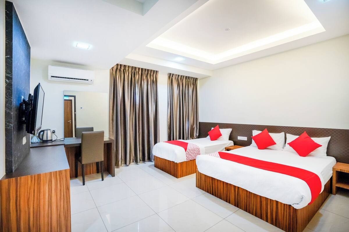 A hotel room with two beds, a desk, a chair, and an air conditioning unit.