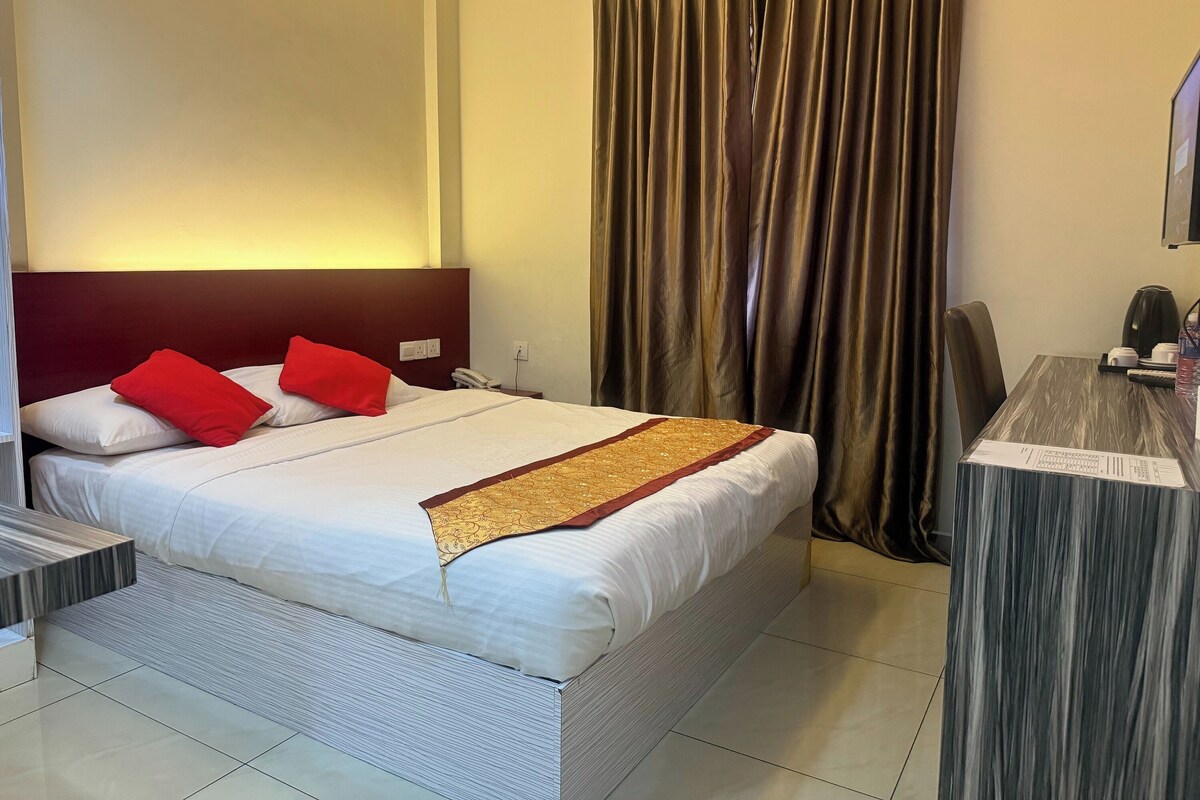 Habitación de hotel con cama, escritorio, silla, teléfono y cortina.