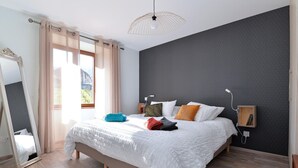 A modern bedroom with a large bed, a bedside table, a mirror, and a ceiling light. - Charming renovated apartment for 4 with terrace in Hunawihr (Hunawihr)