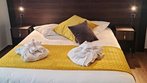 A neatly made bed with a yellow quilt, white and yellow pillows, and two white towels on the bed. - Cozy Alsace Retreat: 2BR, Sauna, Pool Access, Near Vineyards & Colmar (Rouffach)