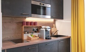 A modern kitchen with dark cabinets, a stainless steel oven, a built-in microwave, and a wooden countertop with a coffee machine. - Cozy Alsace Retreat: 2BR, Sauna, Pool Access, Near Vineyards & Colmar (Rouffach)