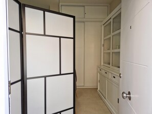 A hallway with a sliding door leading to a room with a cabinet and a door with a silver handle.