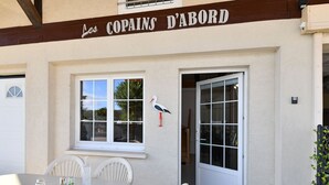 A building with a sign reading "Les COPAINS D'ABORD" and a white table with chairs outside. - Beautiful Country Home with Terrace, Close to Amenities & Highways, Sleeps 5 + Baby (Baldersheim)