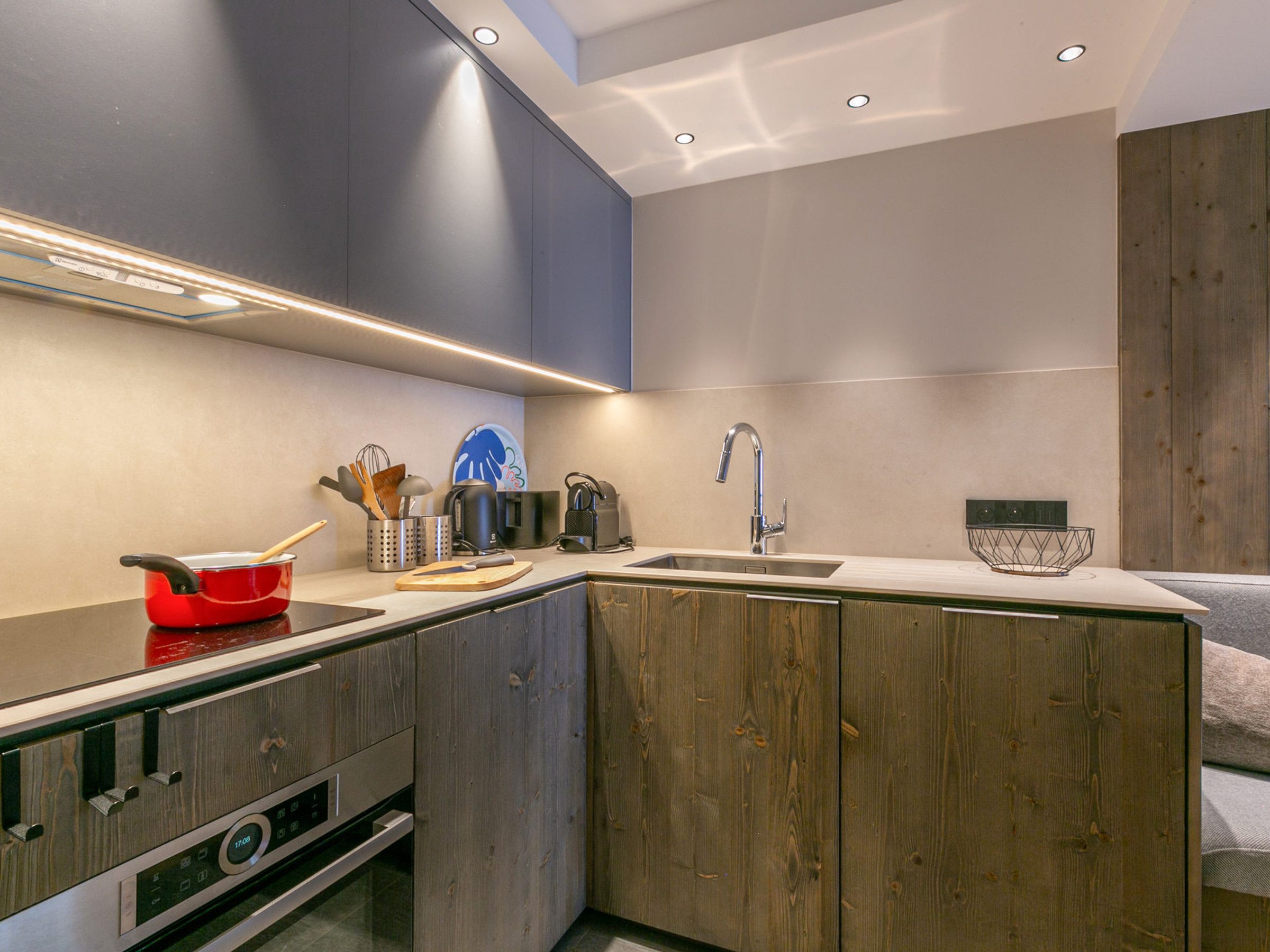 A modern kitchen with a built-in oven, a sink, and a wooden cabinet.