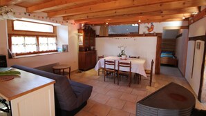 A cozy room with a dining table, chairs, a sofa, a cabinet, and a radiator. - Charming Alsatian Farmhouse: 2 Terraces, BBQ, Accessible, Near Vosges – Sleeps 6 (Bretten)