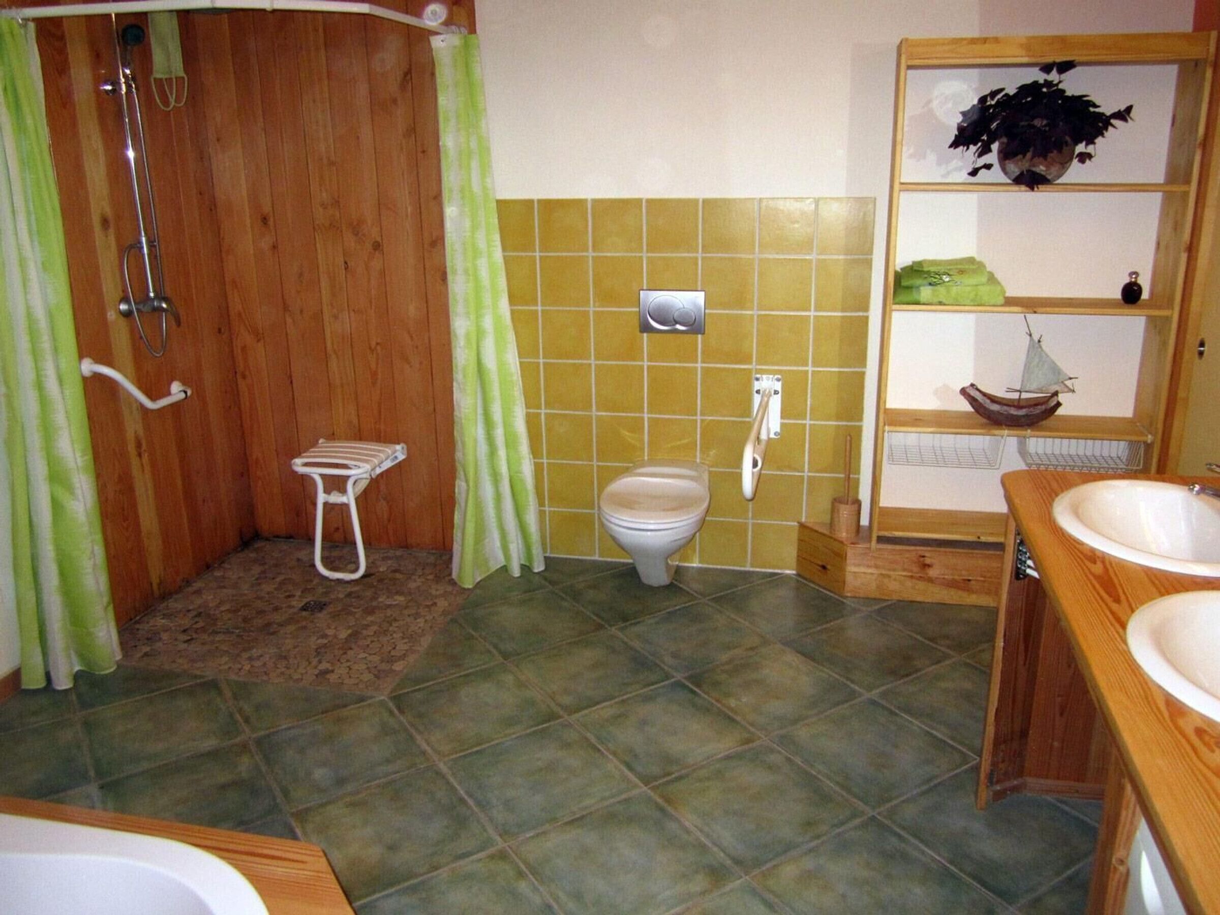 Un baño con cabina de ducha de madera, un inodoro, un lavabo y un estante con una planta.