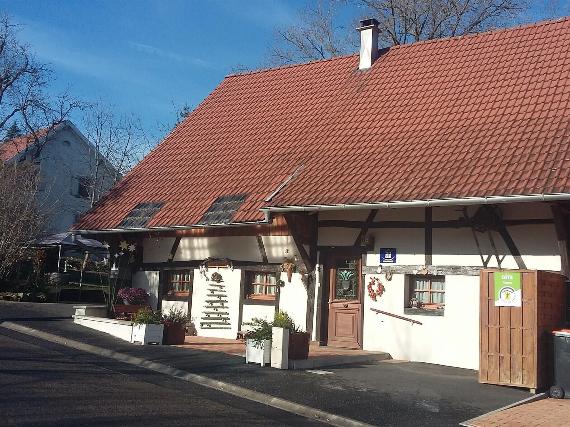 Een traditioneel gebouw met een rood pannendak, een houten deur en een klein portaal met potplanten.