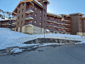 Un hôtel à plusieurs étages, doté de balcons, d’une fondation en pierre et surplombant une piste de ski.