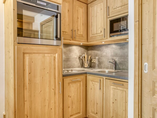A kitchen with wooden cabinets, stainless steel appliances, and a tiled backsplash.