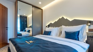 Una habitación de hotel con una cama grande, un espejo, un armario y una lámpara fijada a la pared.
