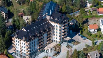 Un hôtel à plusieurs étages, doté d’un design moderne, comprenant une cour intérieure et un parking pouvant accueillir plusieurs voitures.