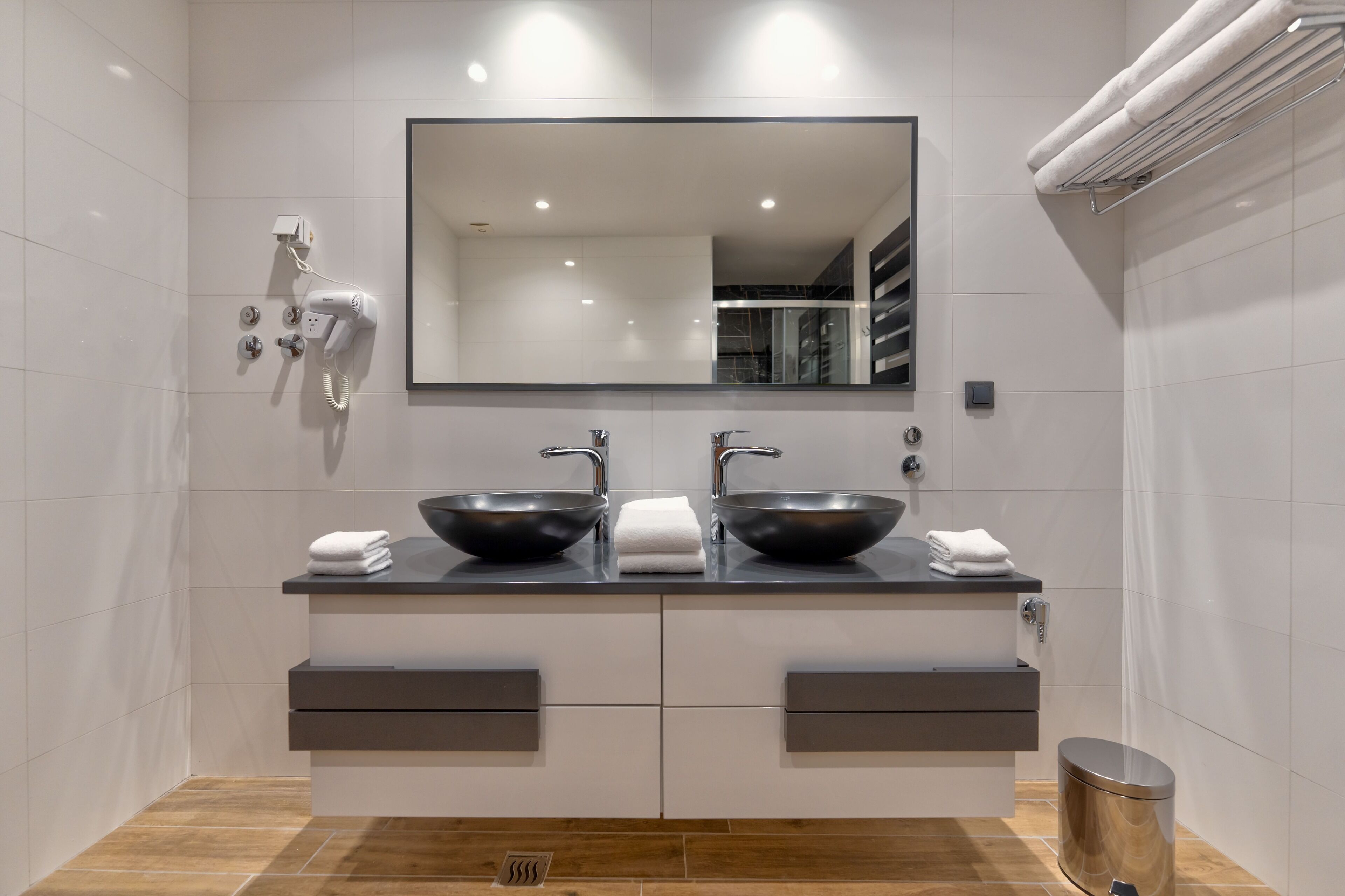 A modern bathroom with two black sinks, a large mirror, and a towel rack.