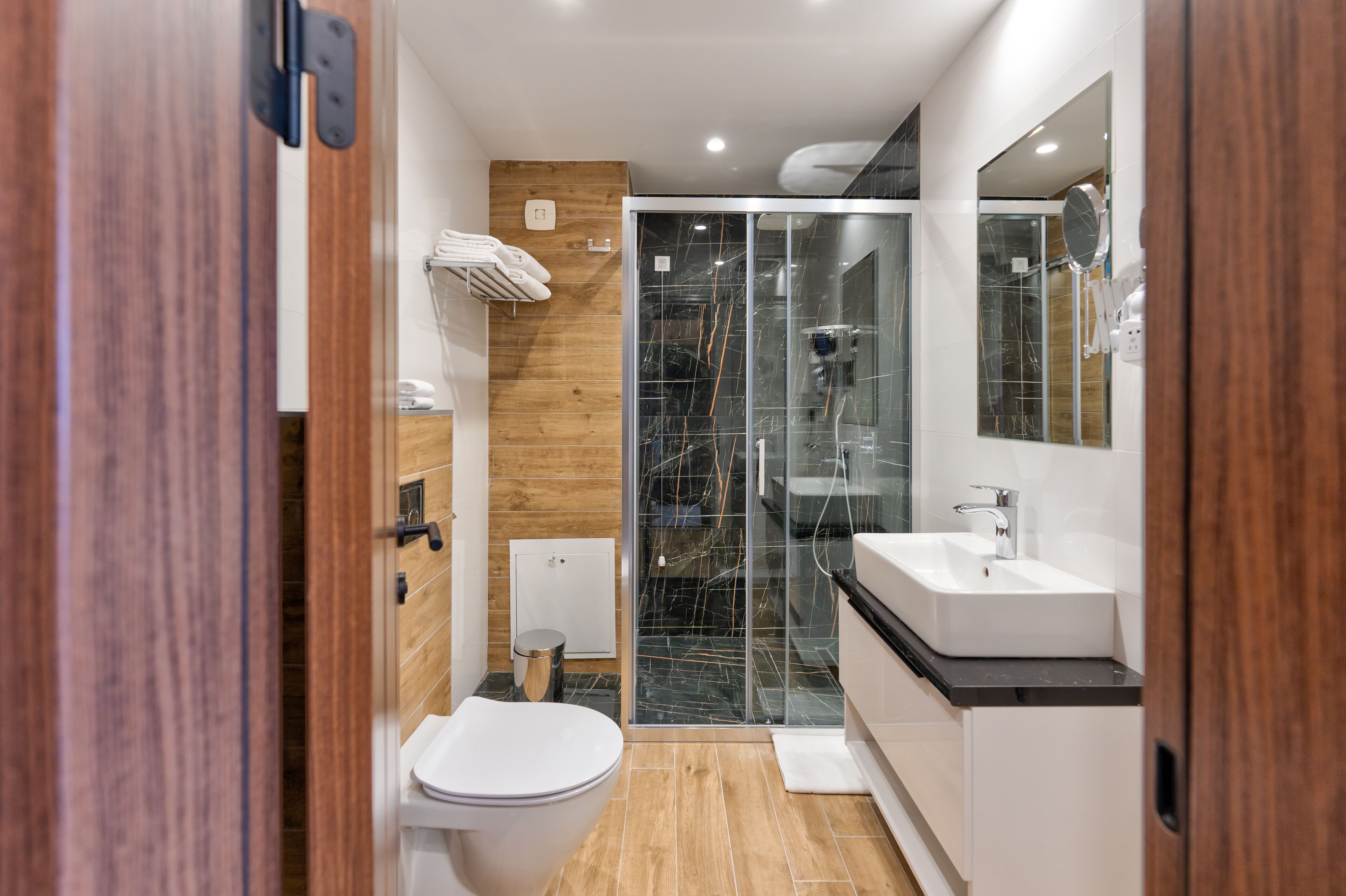 Un baño moderno con cabina de ducha de vidrio, inodoro blanco y tocador con lavamanos.