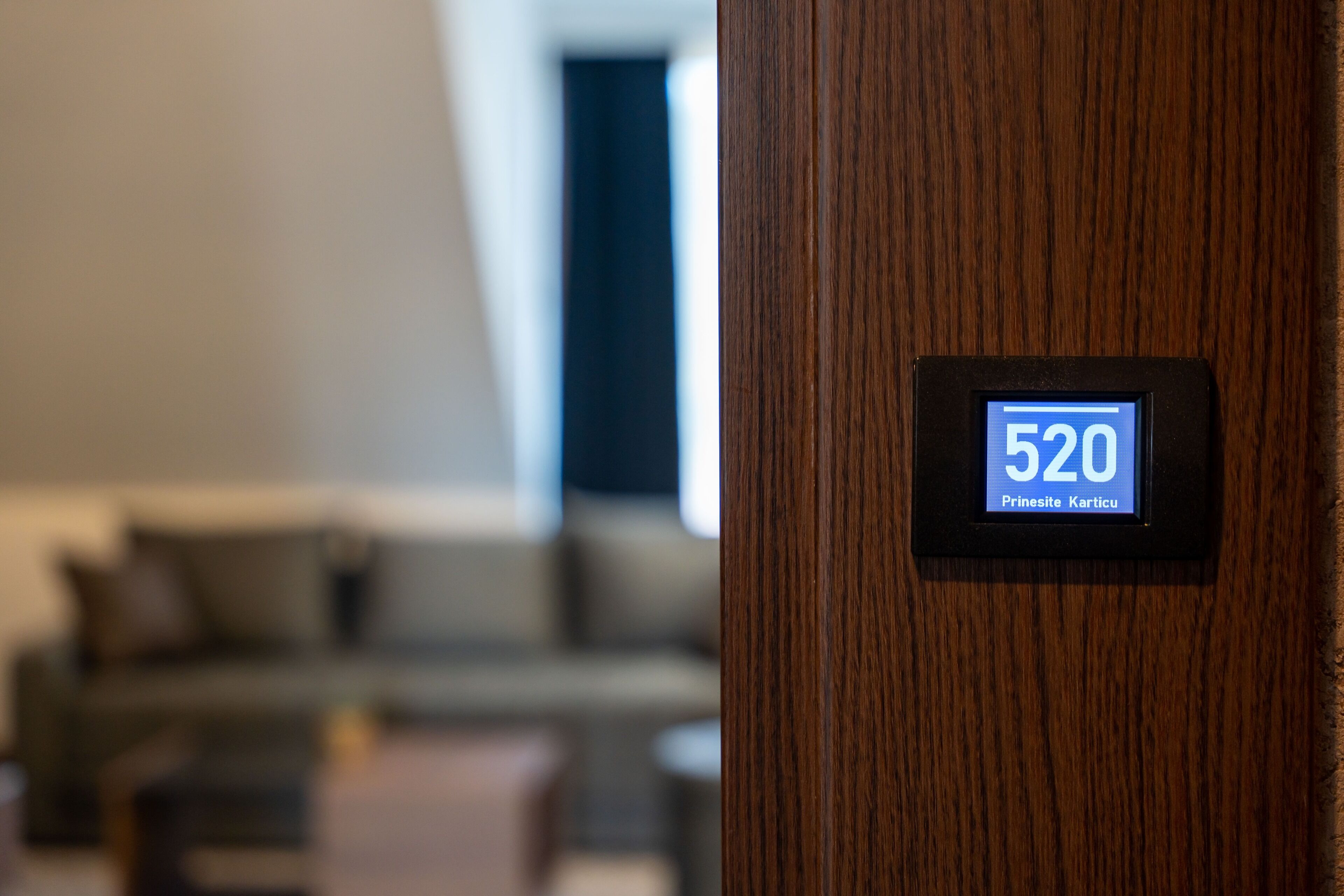 Une porte en bois dotée d’un écran numérique affichant le chiffre 520 et le texte « Prinesite Karticu ».