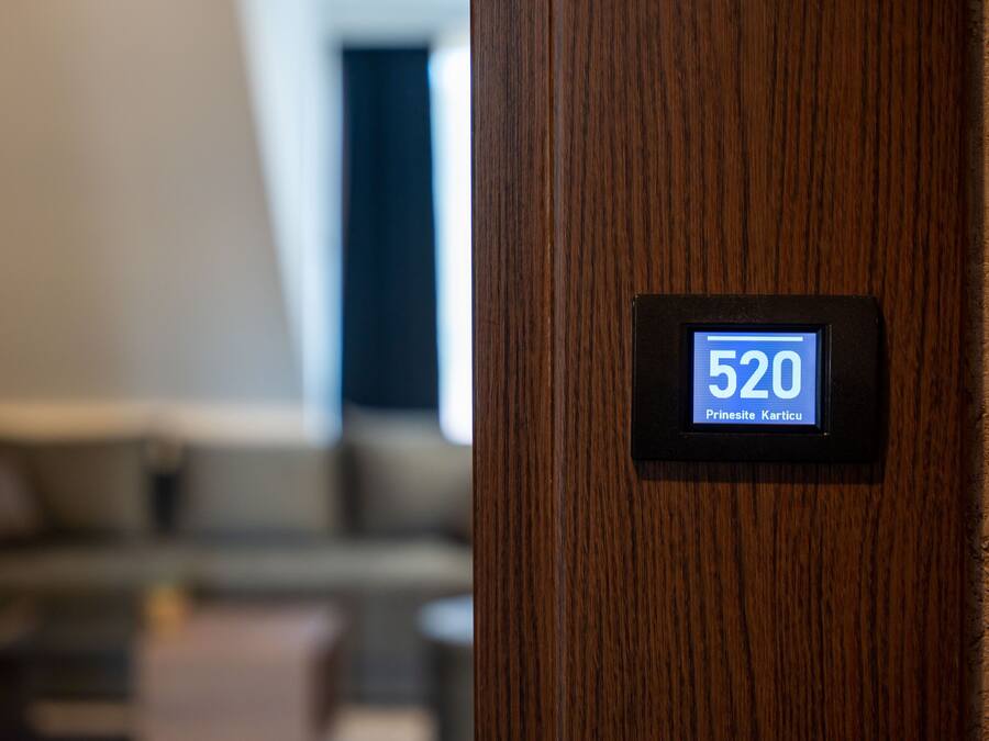 Une porte en bois dotée d’un écran numérique affichant le chiffre 520 et le texte « Prinesite Karticu ».
