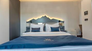 A modern hotel room with a bed, a nightstand, and a wall-mounted thermostat.