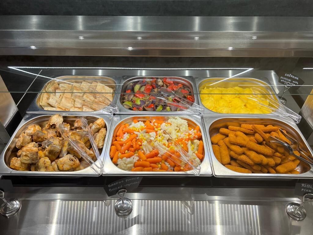 Ein Buffet mit verschiedenen Speisen, darunter Chicken Wings, gemischtem Gemüse und Käse-Sticks.