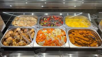 Ein Buffet mit verschiedenen Speisen, darunter Chicken Wings, gemischtem Gemüse und Käse-Sticks.