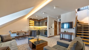 Un apartamento loft moderno con cocina, comedor y sala de estar. Cuenta con una escalera, un televisor de pantalla plana y un amplio ventanal que proporciona luz natural.