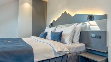 Una habitación de hotel moderna con cama, mesita de noche y cabecera con diseño de montaña.