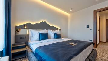 A modern hotel room with a large bed, a headboard with a mountain design, bedside tables, and a carpeted floor.