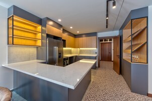 Una cocina moderna con una isla grande, electrodomésticos integrados y estanterías de madera.