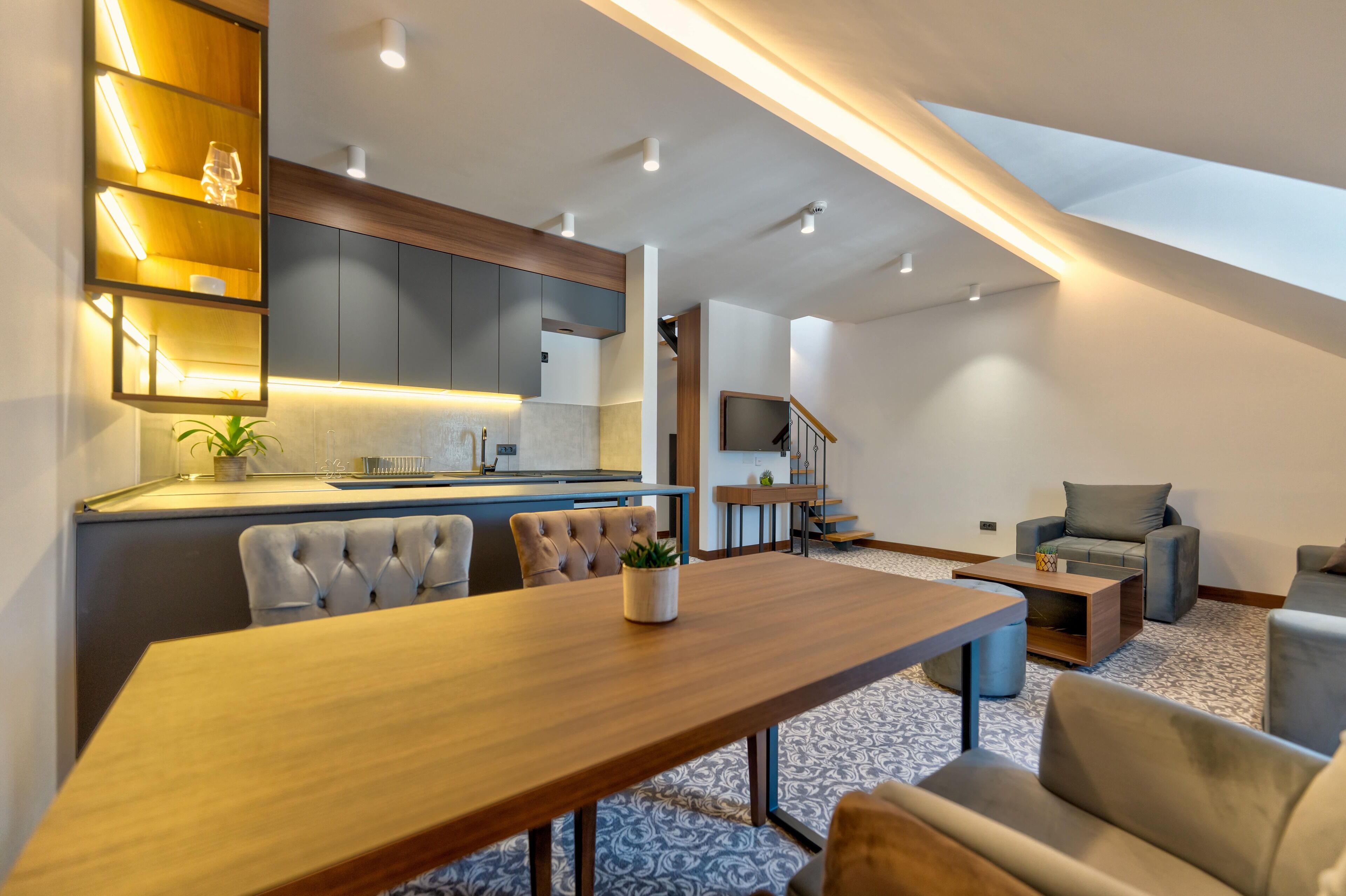 A modern living space with a dining area, kitchen, and seating area.